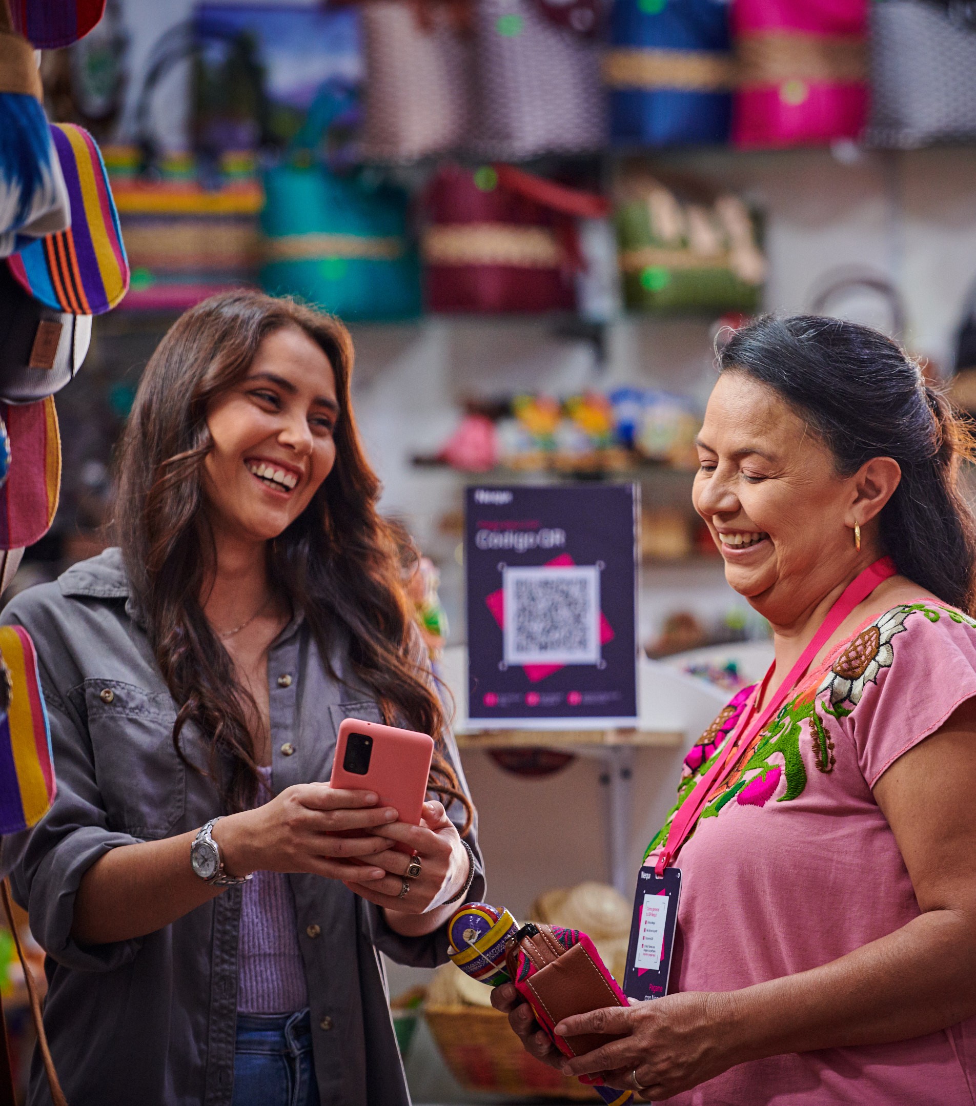 Mujeres comerciantes sonriendo y usando Nequi en su negocio